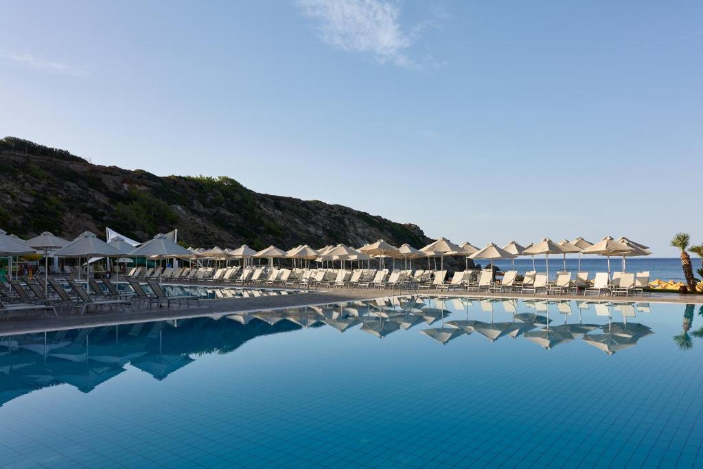 马克里亚罗斯Atlantica Mikri Poli Crete的一个带椅子和遮阳伞的游泳池以及大海