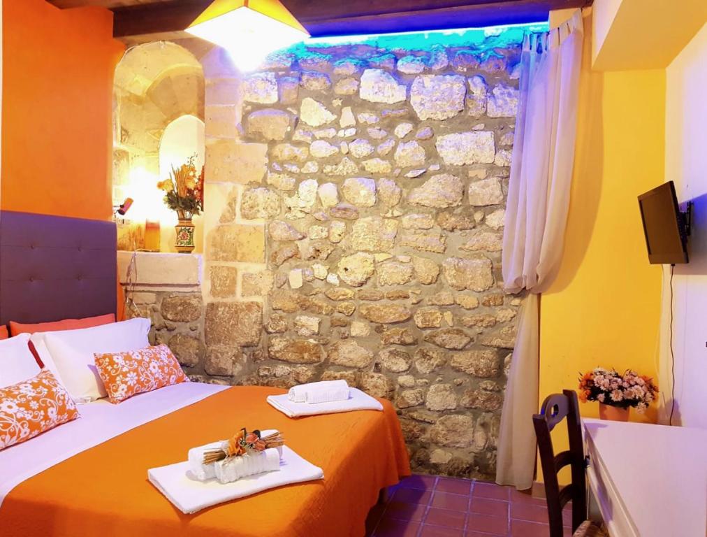 锡拉库扎特雷阿尔奇旅馆的一间卧室设有两张床和石墙