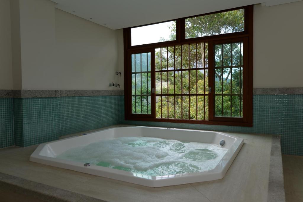 多明戈斯马丁斯Vista Azul Apart Hotel - Vista Pinheiros的窗户客房内的大浴缸