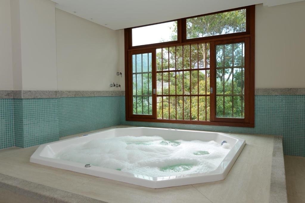 AracêVista Azul Apart Hotel - Vista Pinheiros的带窗户的浴室设有大浴缸