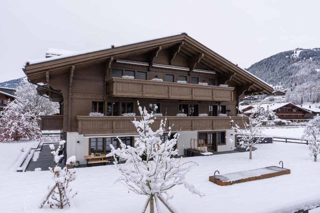 格施塔德Swiss Hotel Apartments - Gstaad的一座大建筑,地面上积雪