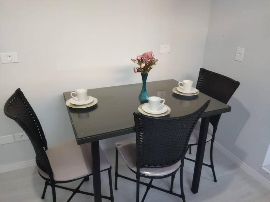 雅卡雷伊Kitnet 1 - próximo ao centro de Jacareí的黑色餐桌,带椅子,花瓶