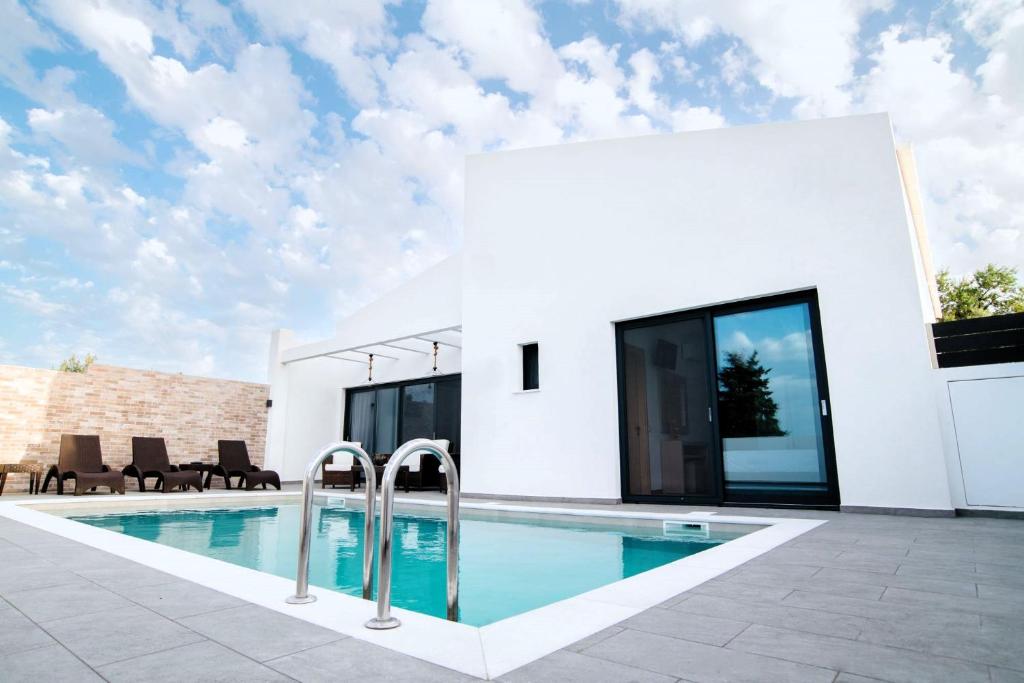 伊奥斯克里克斯Villa Etoile的一座白色的房子,前面设有一个游泳池