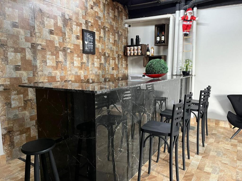 巴西利亚Riacho HOTEL的一间酒吧,里面设有黑色凳子和砖墙