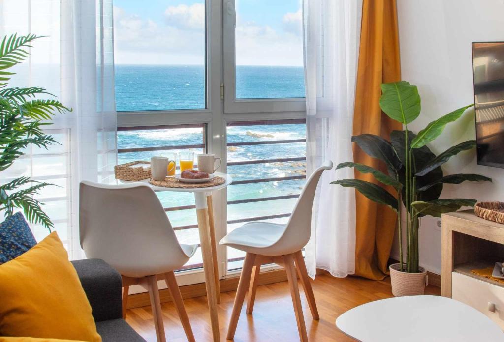 马尔皮卡AG Miramar Malpica x4 vistas playa Costa da Morte的客厅在窗户前配有桌椅
