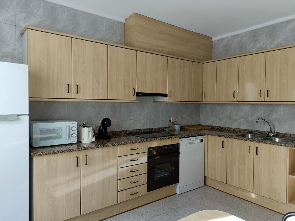 坎普罗东Muralla的厨房配有木制橱柜和白色微波炉