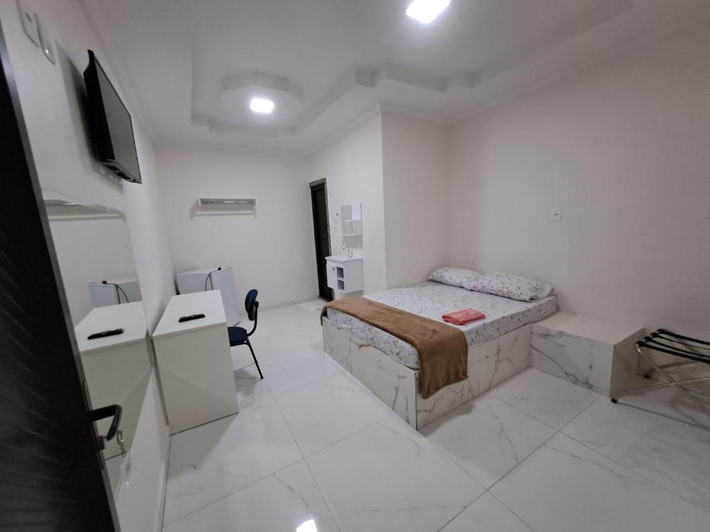 马瑙斯3D Hotel的一间白色的房间,配有一张床和一台电视机