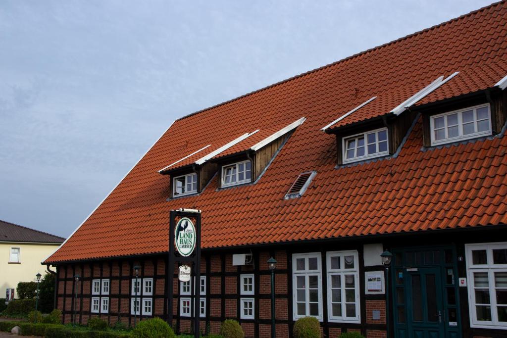 LastrupLandhaus Lastrup的一座带橙色屋顶的建筑,上面有时钟