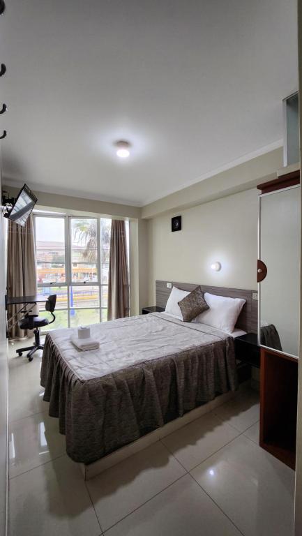 塔克纳HOSTAL EL REFLEJANTE的一间卧室配有一张床、一张书桌和一个窗户。