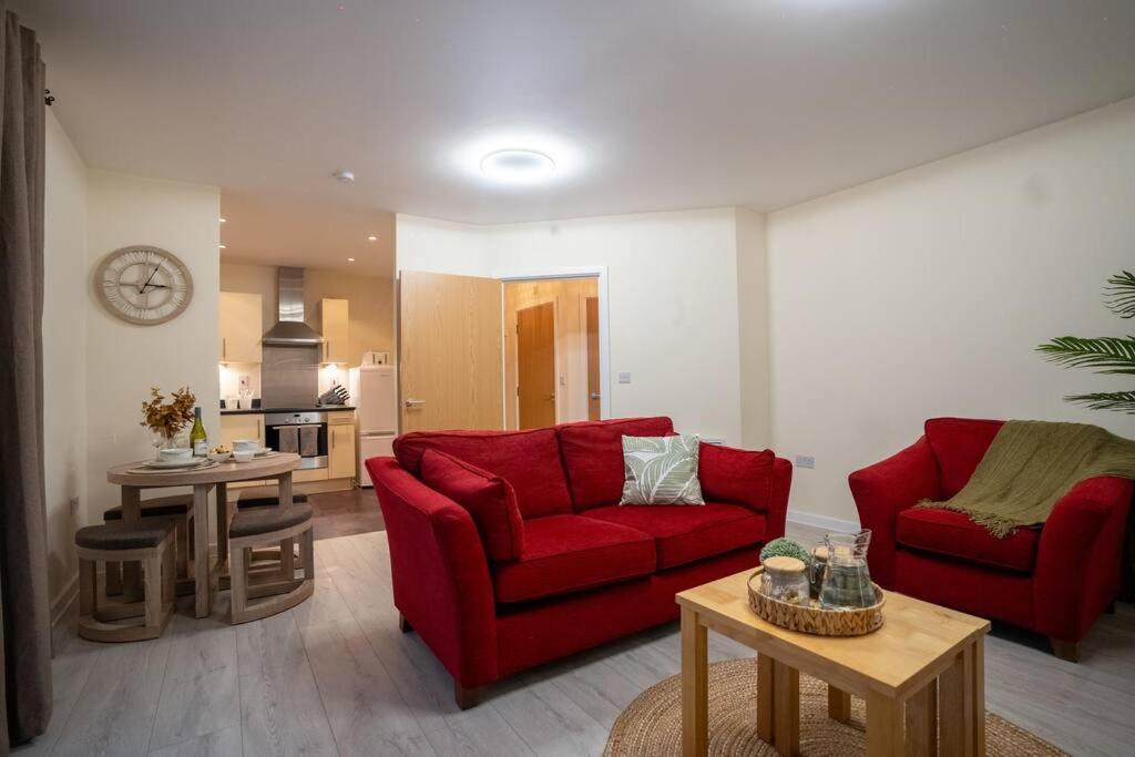 斯蒂夫尼奇Cosy 2 Bedroom flat in Stevenage的一间带两张红色沙发的客厅和一间厨房