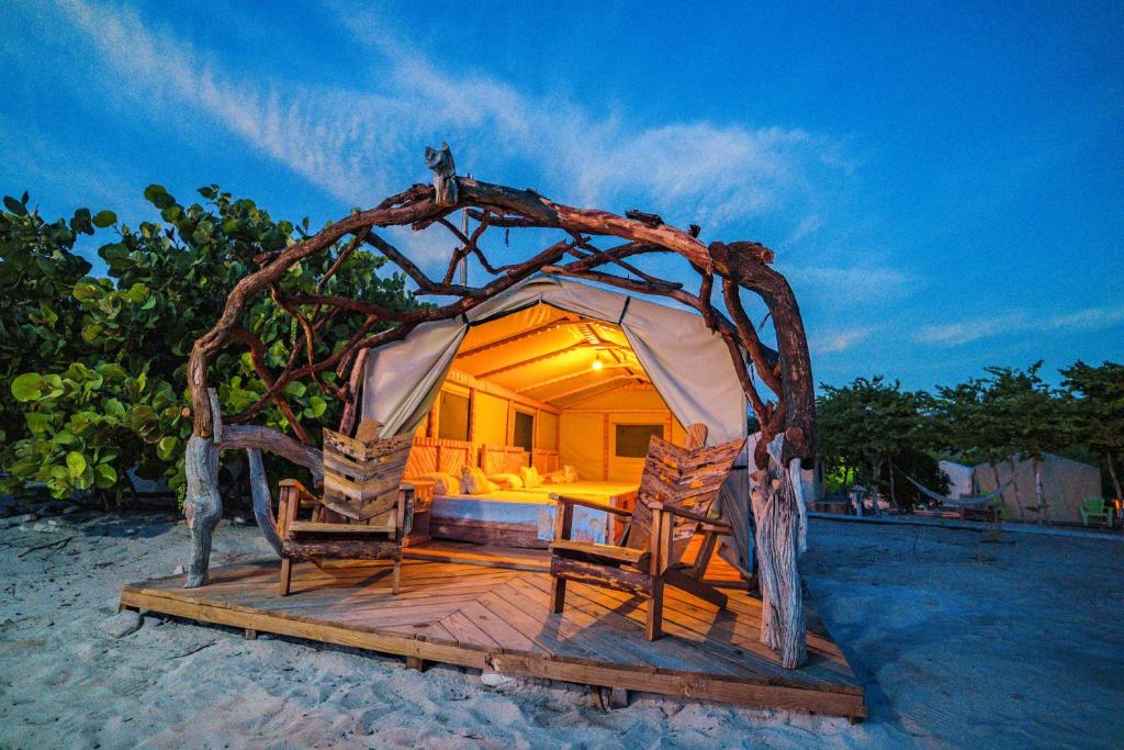 佩德纳莱斯Glamping EcoLodge Cueva De Las Aguilas的海滩上带一张床和两把椅子的房间