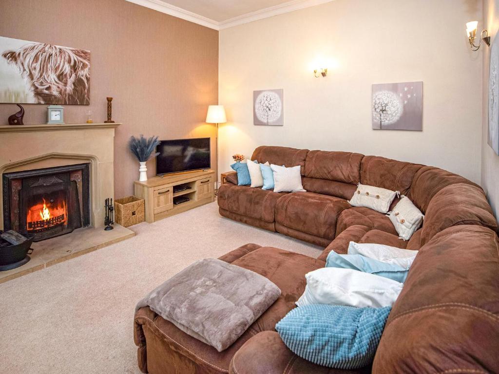 AllantonPurves Cottage的客厅设有棕色沙发和壁炉