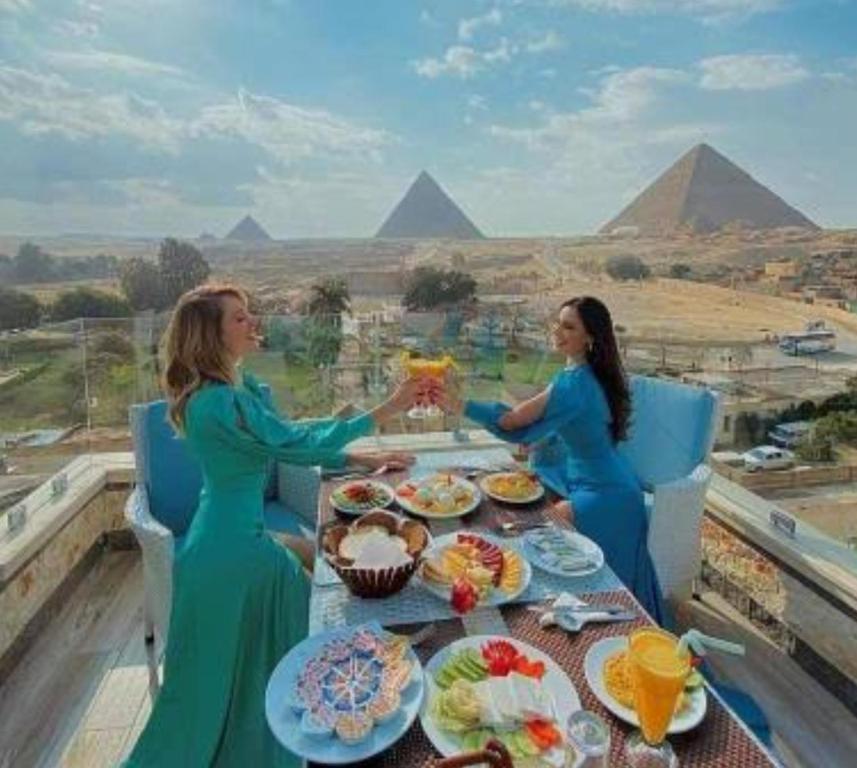 GhaţāţīRoyal pyramids residential的两个坐在桌子边的女人,在金字塔前吃着食物