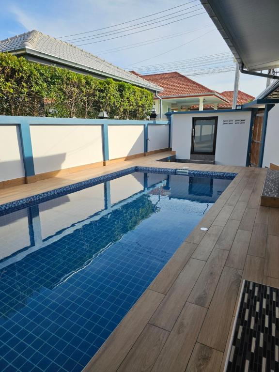七岩Pool Villa Baan Sanook Cha-am的一个带木甲板和房子的游泳池