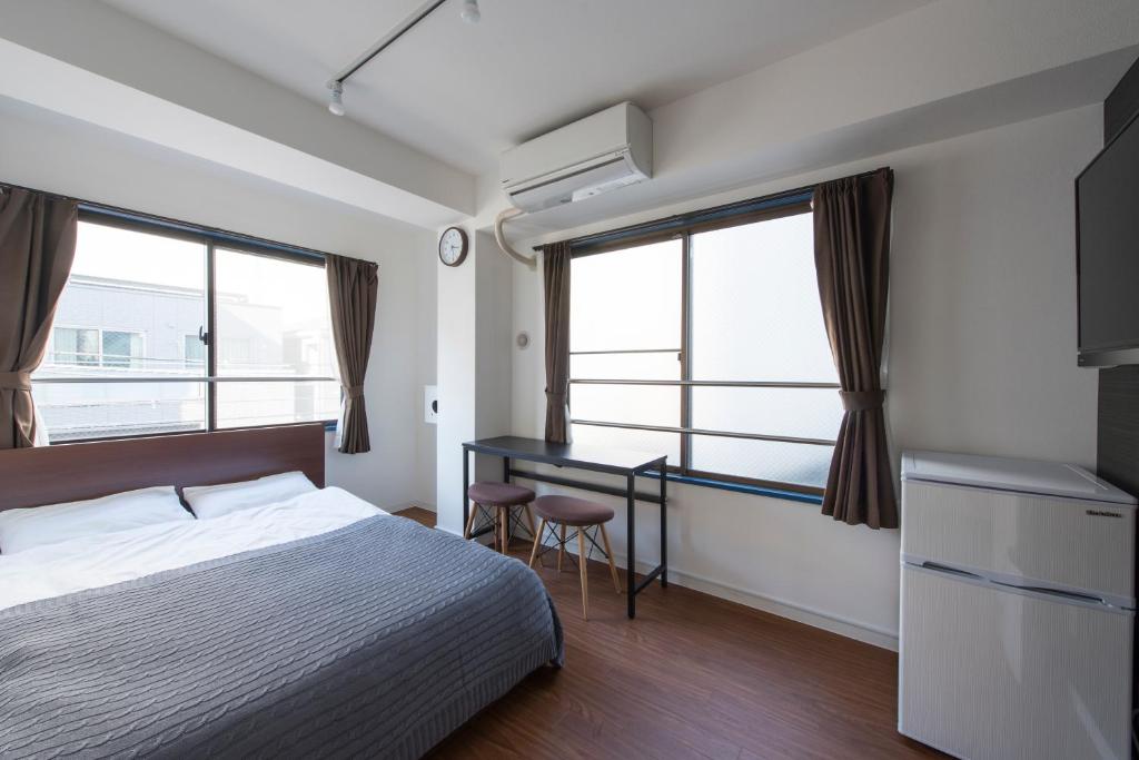 东京KandO Hostel Ueno的卧室配有一张床、一张书桌和窗户。