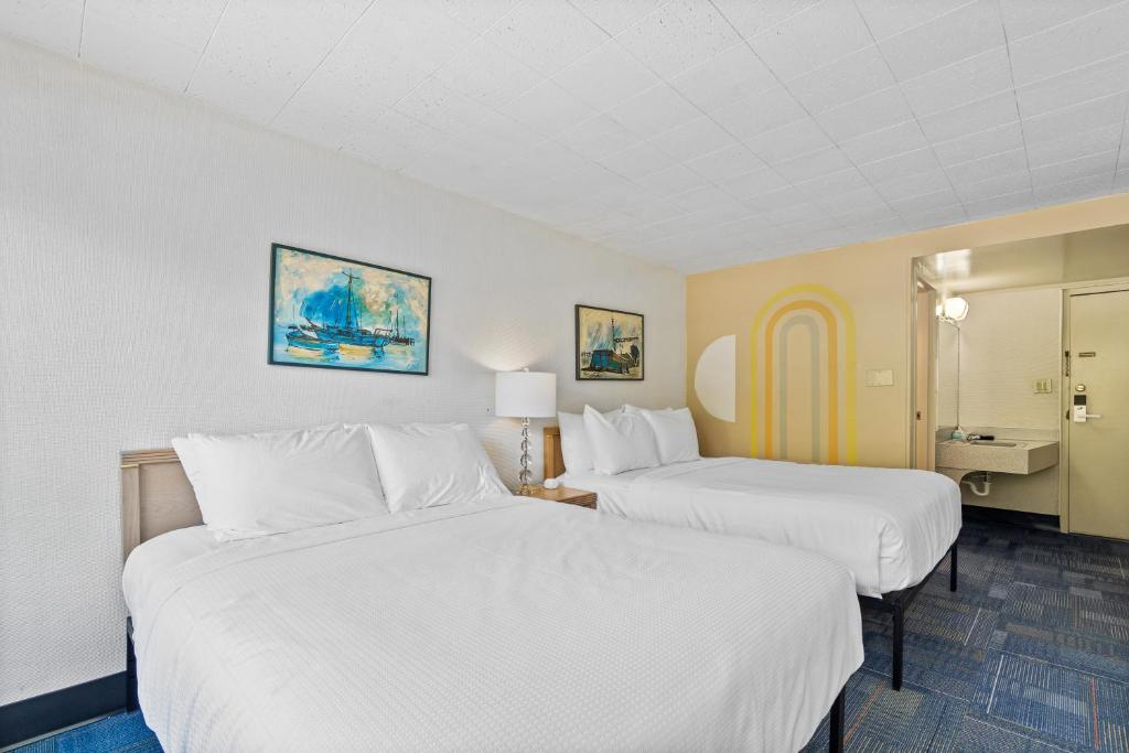 华莱士Stardust Motel Wallace的配有白色床单的酒店客房内的两张床