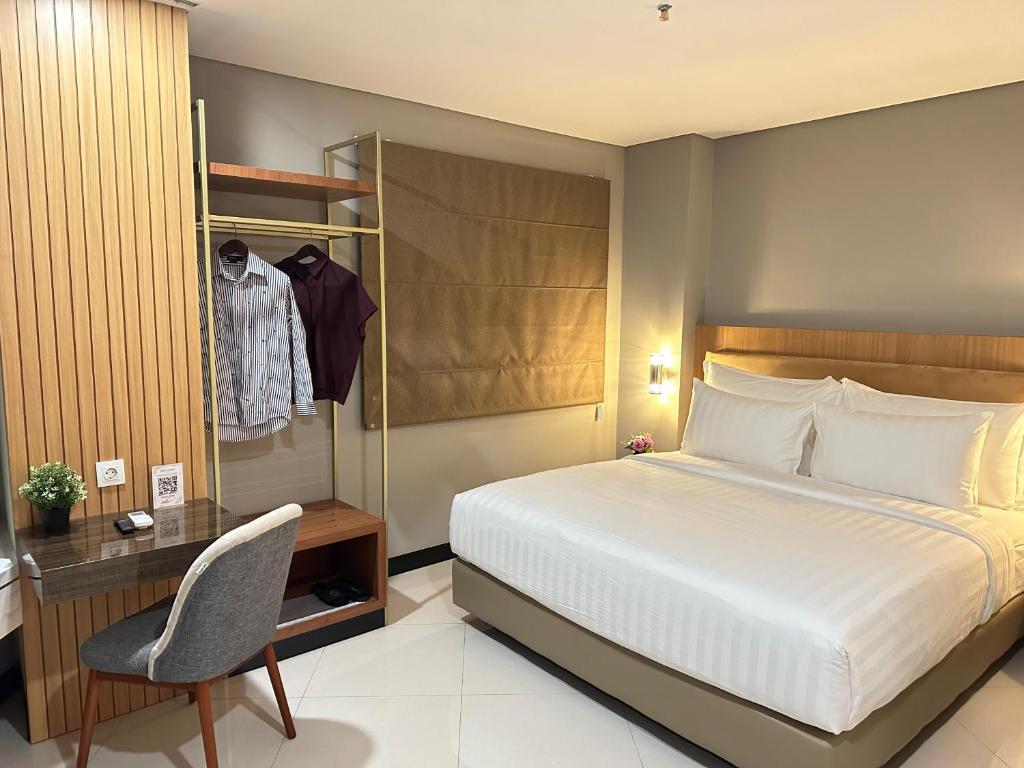 泗水d'primahotel Jemursari Surabaya的一间卧室配有一张床、一张桌子和一把椅子