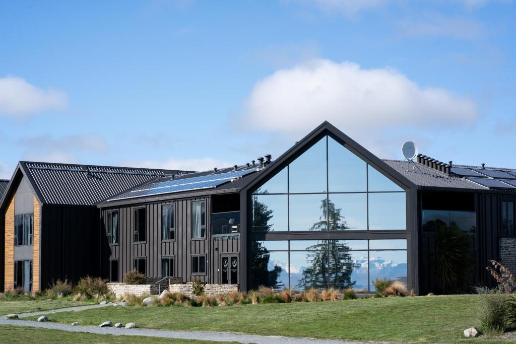 特卡波湖Haka House Lake Tekapo的一座大型黑色建筑,设有玻璃窗