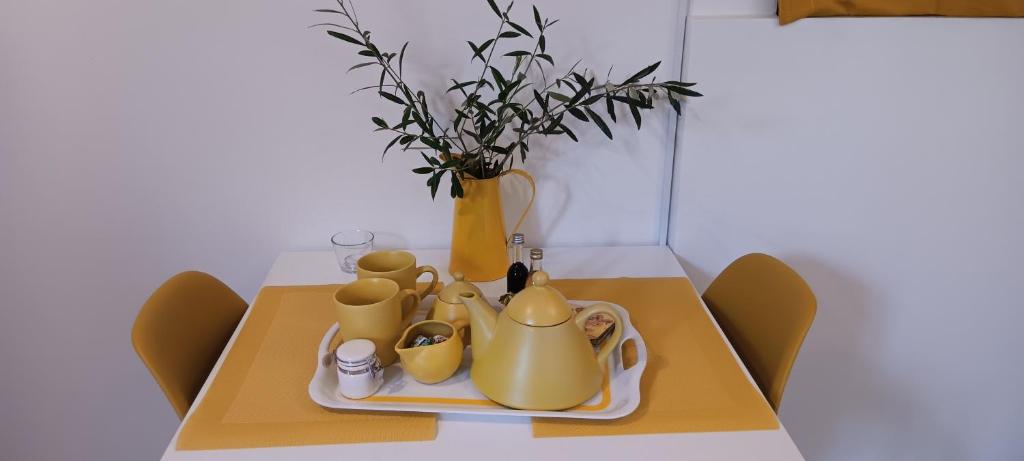 雅典Athenian Asty Guesthouse的一张带黄茶套装和花瓶的桌子