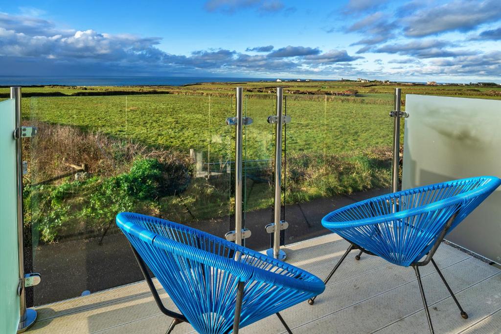 廷塔杰尔Finest Retreats - Treknow Summerhut的阳台设有两把蓝色椅子,享有田野美景