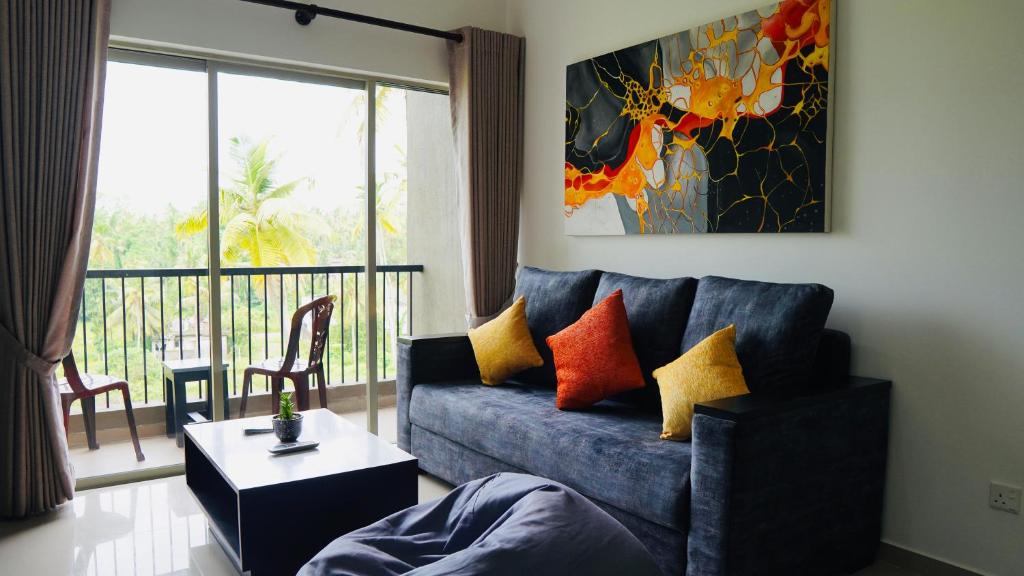 MalabeCoco Nest Colombo Sri Lanka的一间带蓝色沙发的客厅和一个阳台