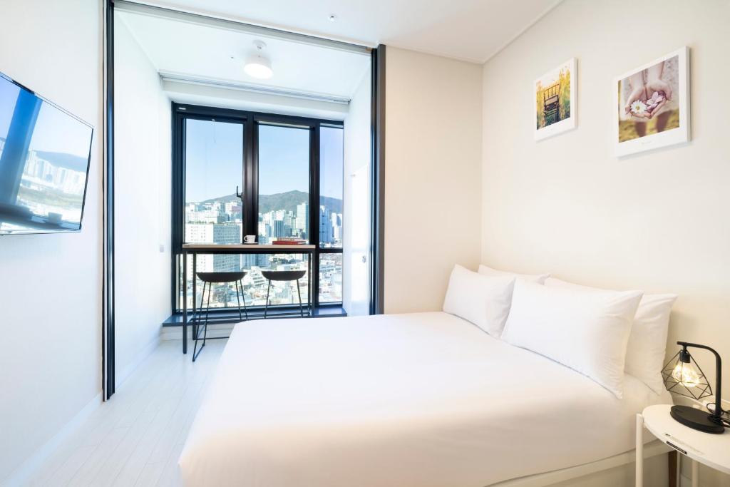 釜山From H Reposant Hotel Busnan Seomyeon的卧室设有白色的床和大窗户
