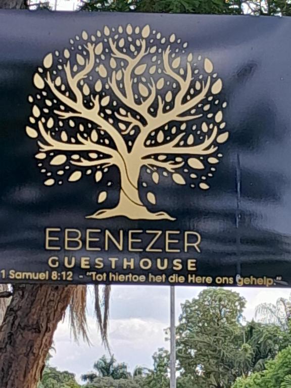 格罗布勒斯达尔Ebenezer Self Catering的建筑物一侧有树的标志