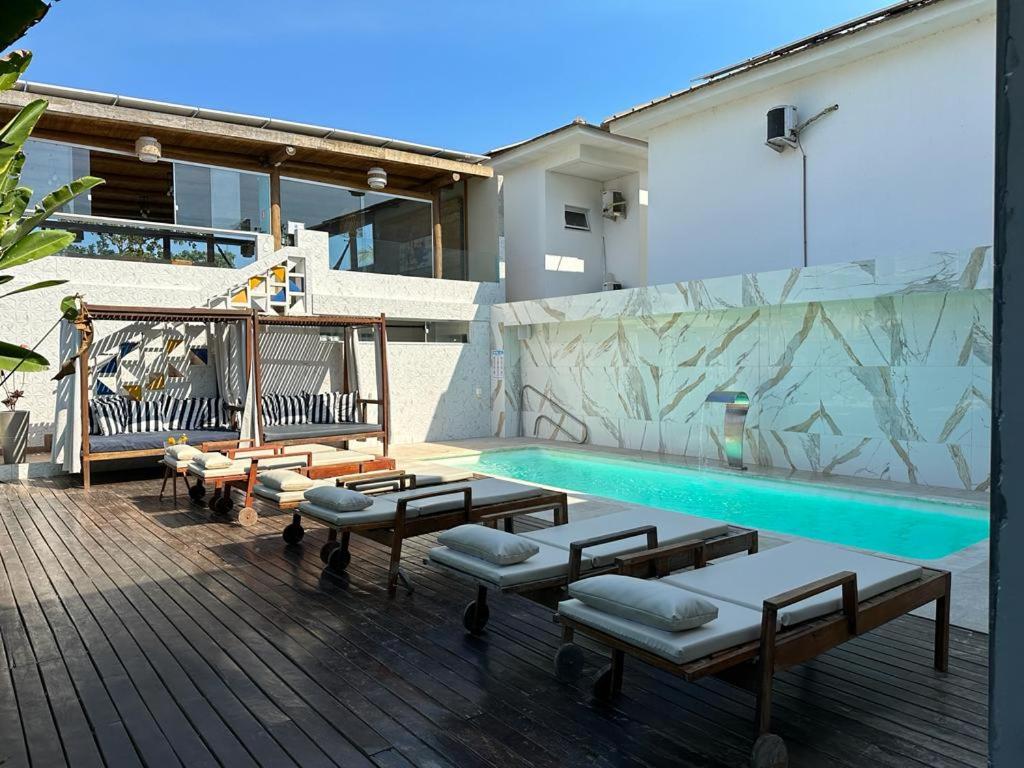 阿拉亚尔达茹达Santorini Beach Hotel的一座带躺椅和长凳的游泳池位于一座大楼旁