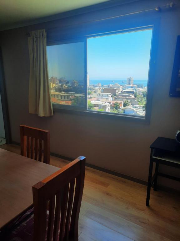瓦尔帕莱索loft vista a la bahía的一间带大窗户和桌子的用餐室