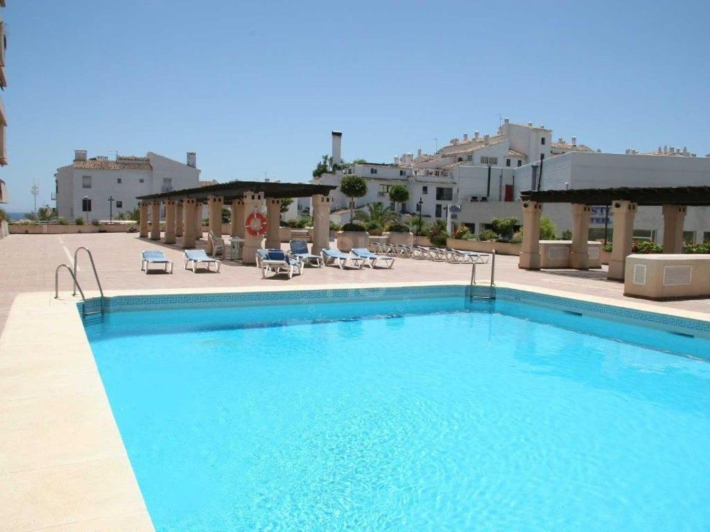 马贝拉LUX Apt Puerto Banus-Pool-Terrace 5 min to beach的一座带椅子和建筑的大型蓝色游泳池