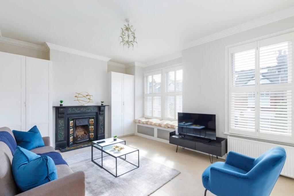 伦敦Tranquil 2BR Fulham Gem with Terrace Near Shops的客厅设有蓝色的沙发和壁炉