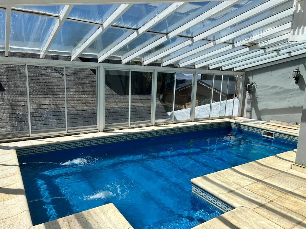 圣卡洛斯-德巴里洛切Casa con pileta climatizada privada的一个带玻璃屋顶的游泳池和一个泳池景