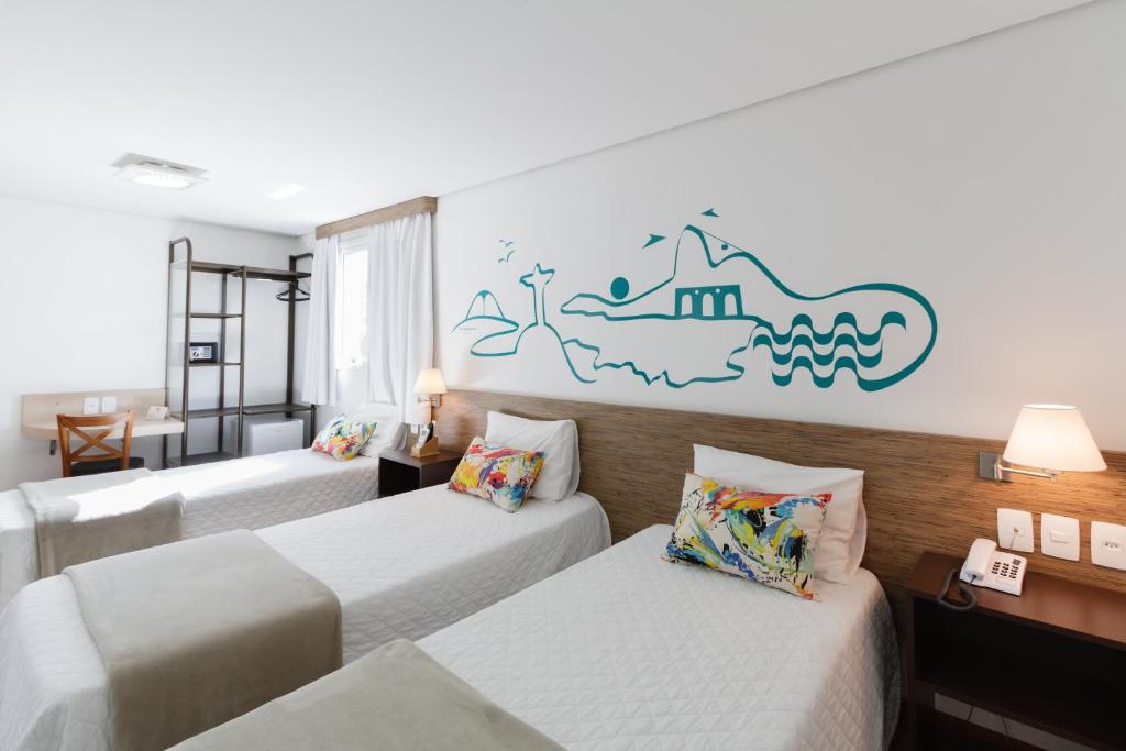 阿雷格里港加里波第商务酒店的酒店客房设有三张床,墙上挂有壁画