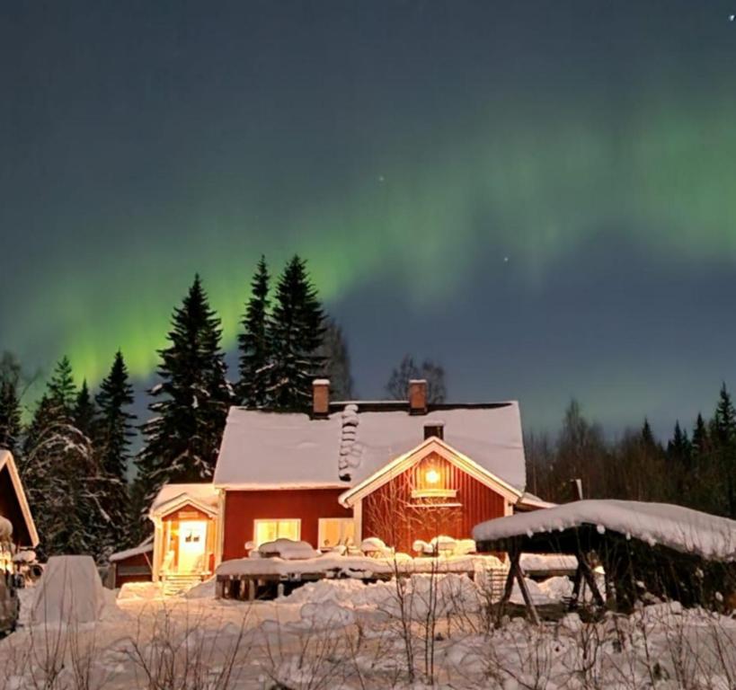 SörsjönStationshuset Dalarna Apartments的天空中光辉灿烂的雪中房子