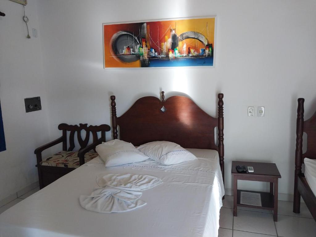 帕拉蒂Pousada Flores da Terra的卧室配有一张带白色床单的床,墙上挂着一幅画