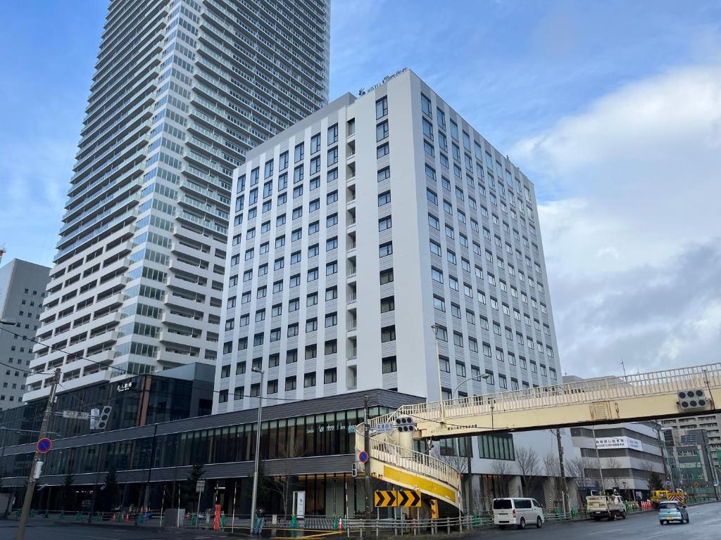 札幌Hotel Emion Sapporo的前面有一辆公共汽车的白色高楼