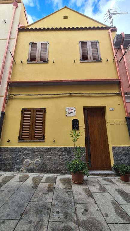 伊格莱西亚斯Casa vacanze Galena的黄色的房子,有两个窗户和门