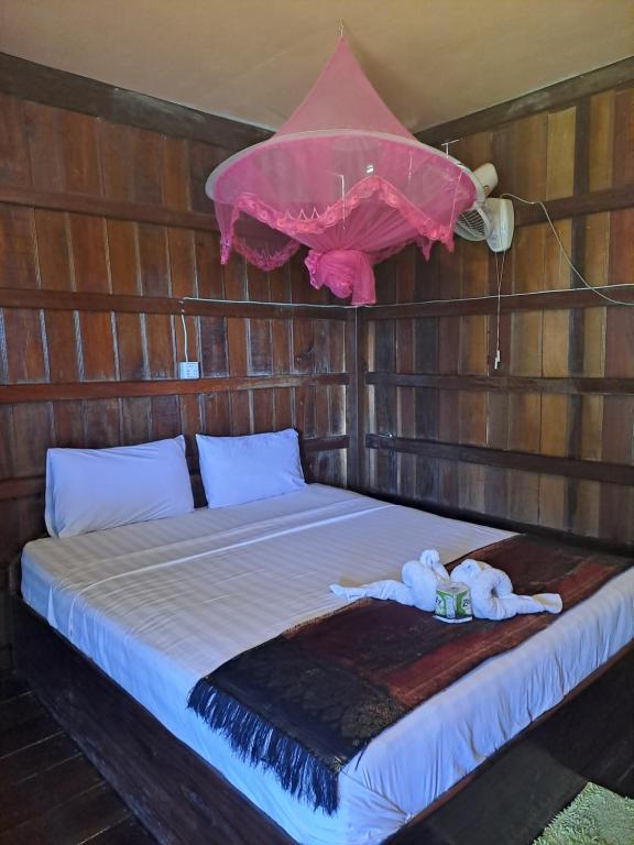 东德岛Riverside Bungalow Don Det的一张位于木制房间的床,配有粉红色的伞