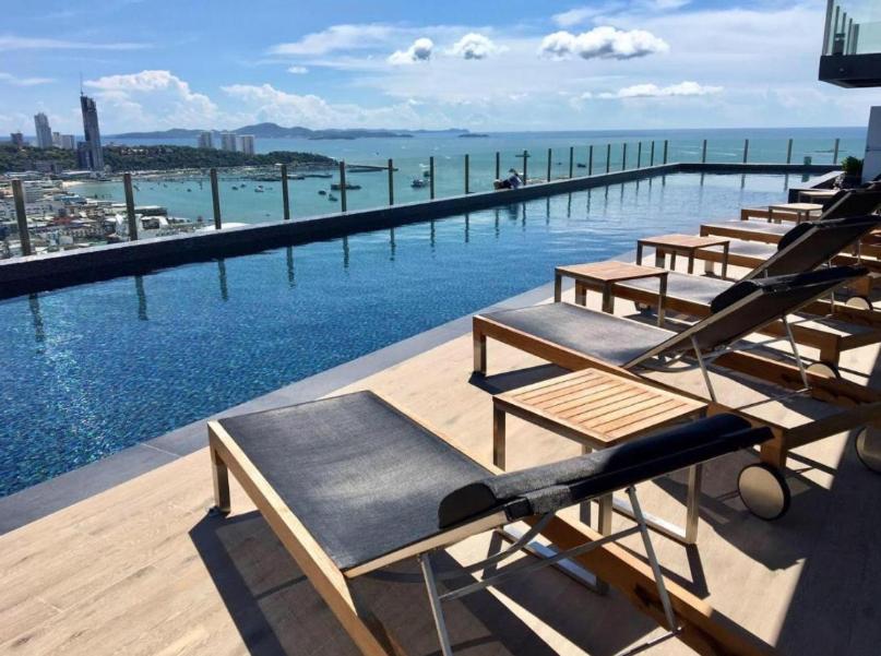 芭堤雅市中心BASE Central PATTAYA Quiet Room with Infinity Pool & Free Netflix的游泳池边的一排躺椅