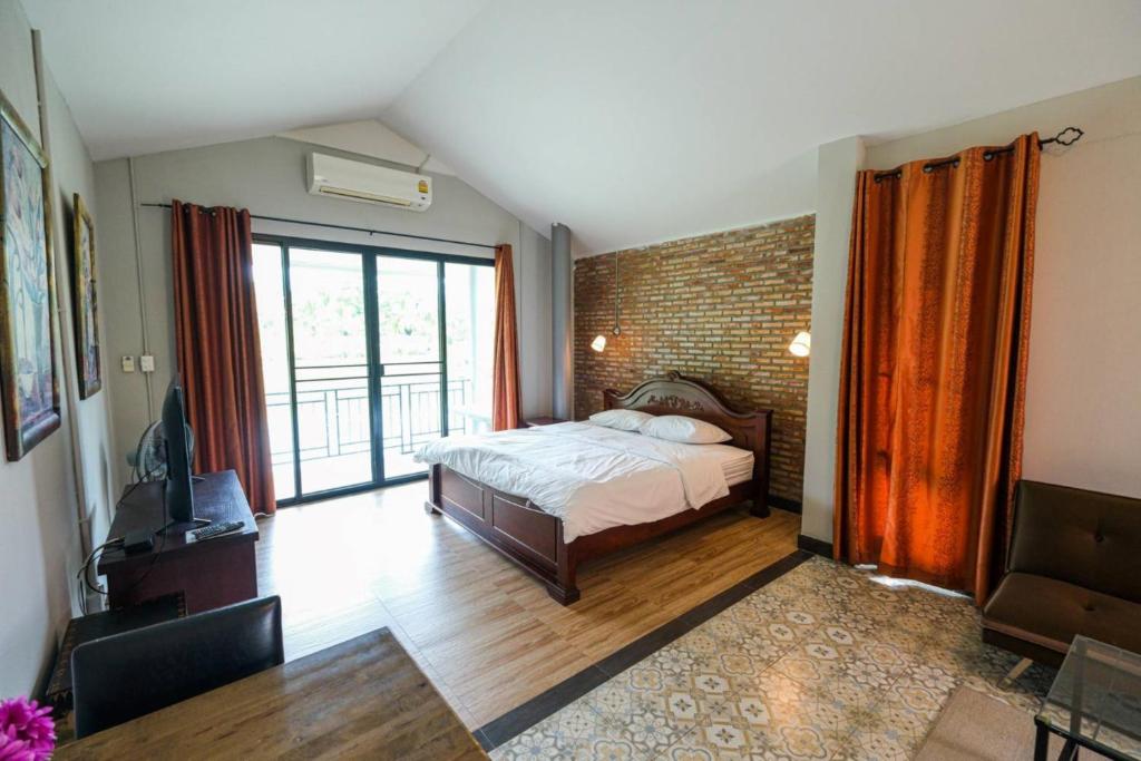 佛统Busaya Resort & Cuisine的一间卧室设有一张床和砖墙