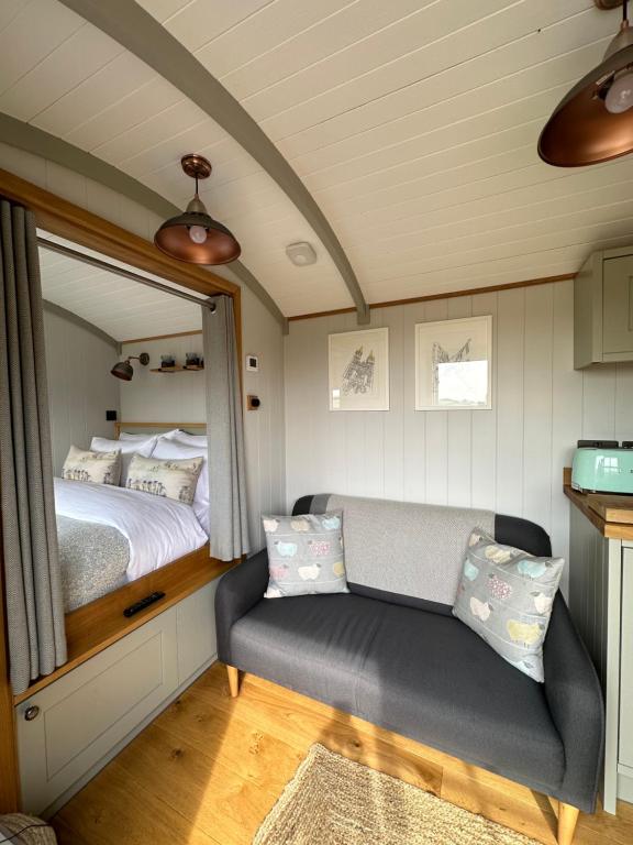 特鲁罗Private and peaceful stay in a Luxury Shepherds Hut near Truro的一间卧室配有一张床、一张沙发和一面镜子