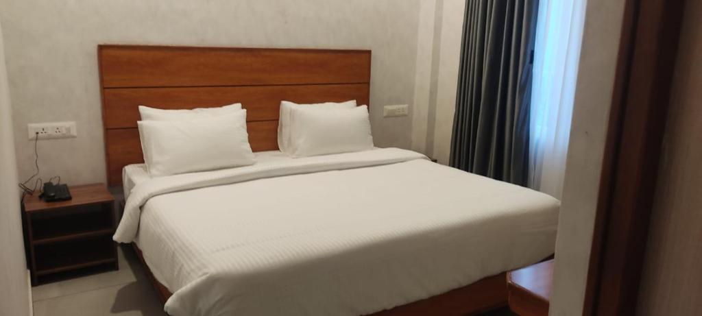 马杜赖CR RIVERA的卧室配有一张白色大床和木制床头板