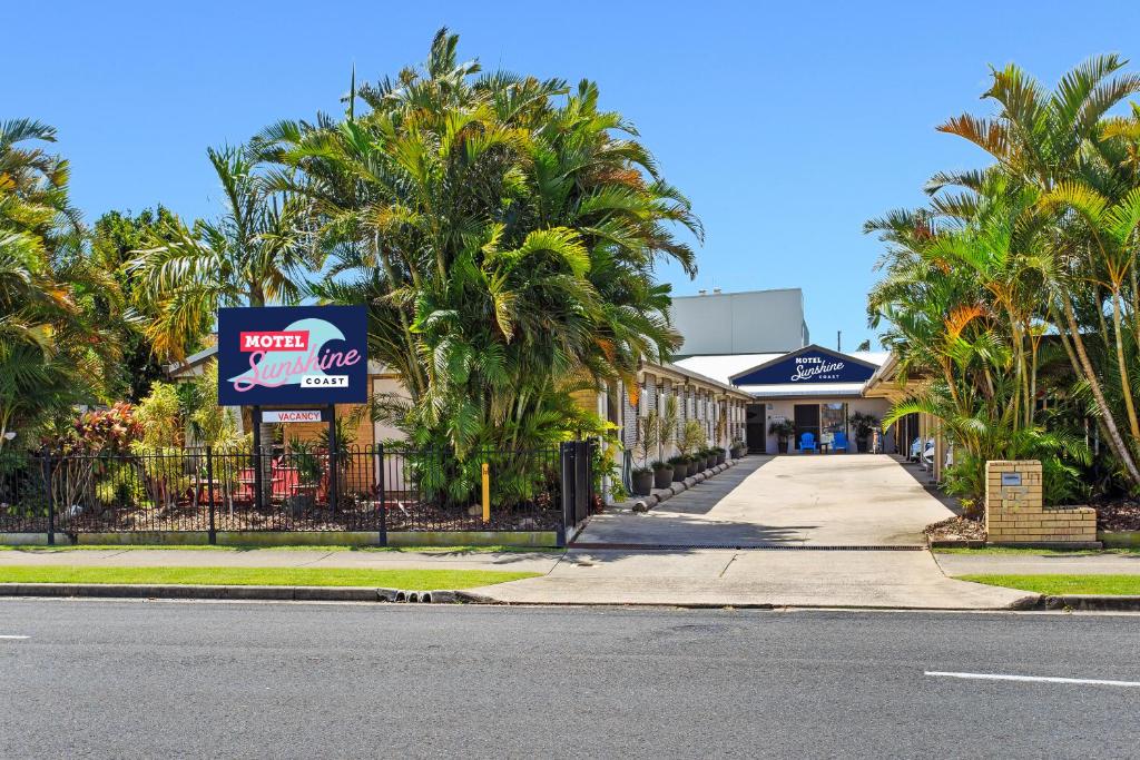 卡伦德拉Motel Sunshine Coast的商店前一条种有棕榈树的街道