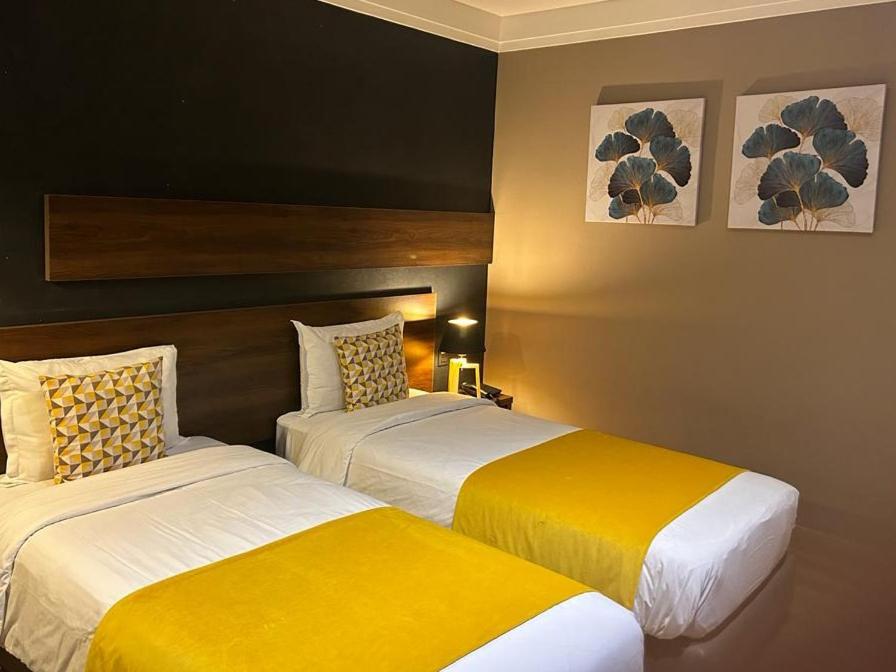 卡萨布兰卡Yto boutique Hotel的两张位于酒店客房的床,配有黄色和白色床单