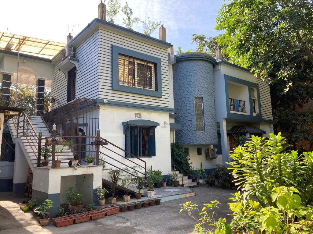 西里古里Anjali HOMESTAY的蓝白色房子,有楼梯和植物