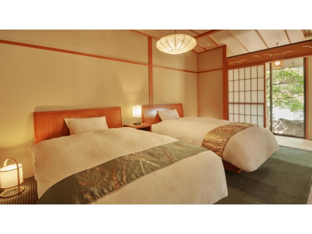 三朝町Mansuirou - Vacation STAY 32146v的一间卧室设有两张床和窗户。