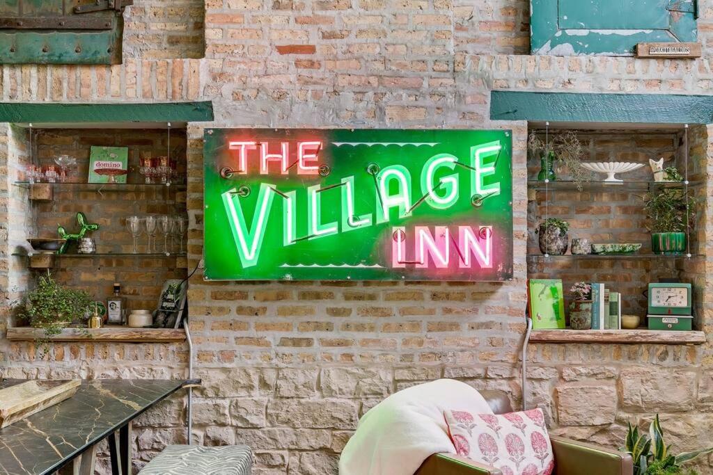 芝加哥The Village Inn by Dakota Gal Digs的村庄旅馆旁的砖墙上的一个标志