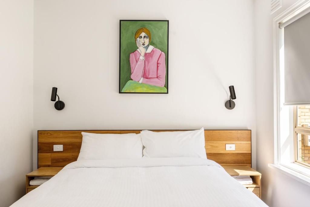 墨尔本MAC South Yarra by Melbourne Apartment Collection的卧室配有一张床,墙上挂有绘画作品