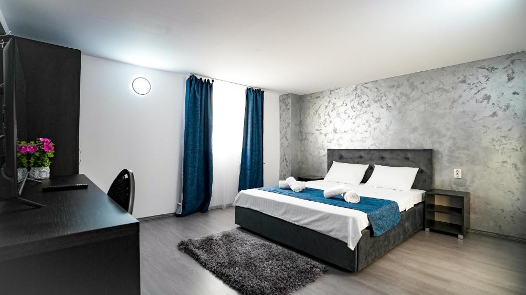 TelegaCasa de pe rau的一间卧室配有一张带蓝色窗帘的床和一张书桌