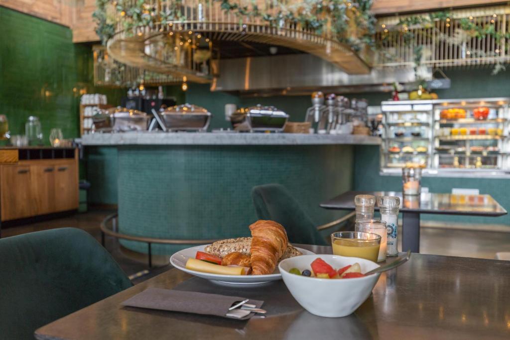 芬克芬Leonardo Hotel Vinkeveen Amsterdam的一张桌子,上面放着一盘面包和一碗水果